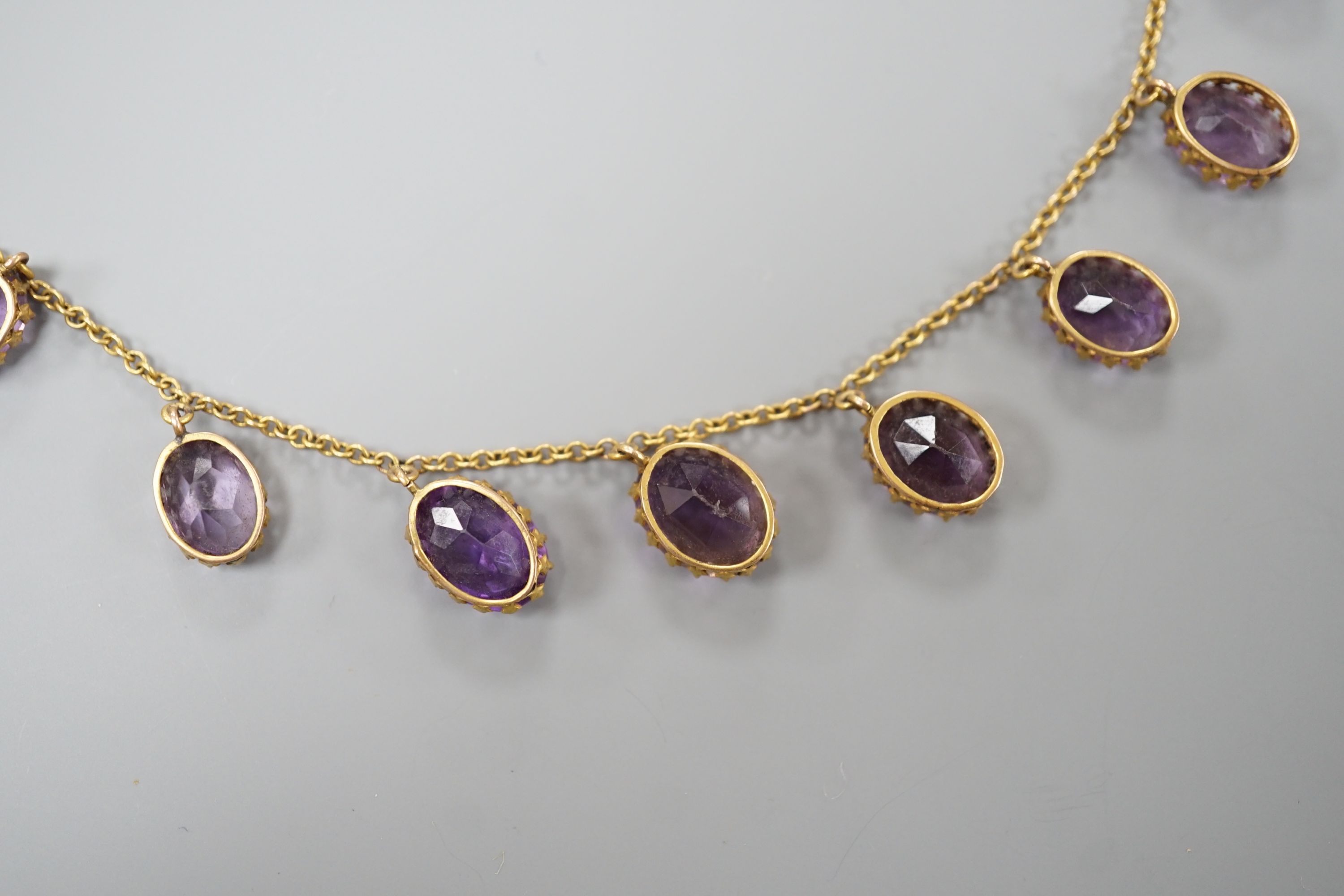 An early 20th century 9ct and graduated oval cut amethyst set drop fringe necklace, 45cm, gross weight 11.8 grams.